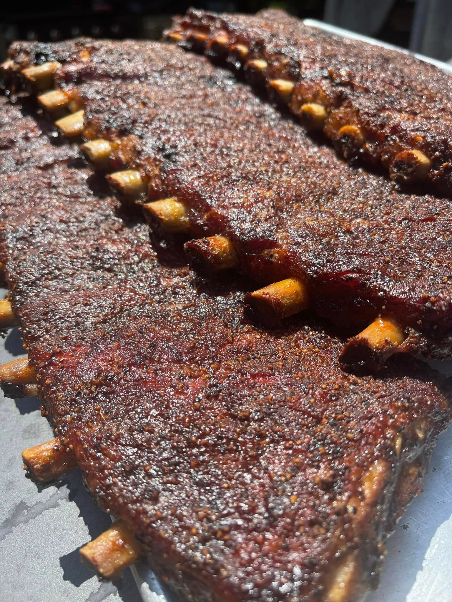 A full rack of smoked pork ribs on a rustic board
